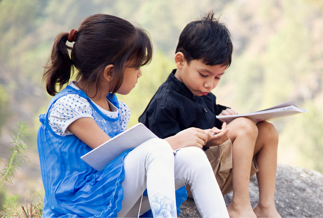 Children reading books outdoors